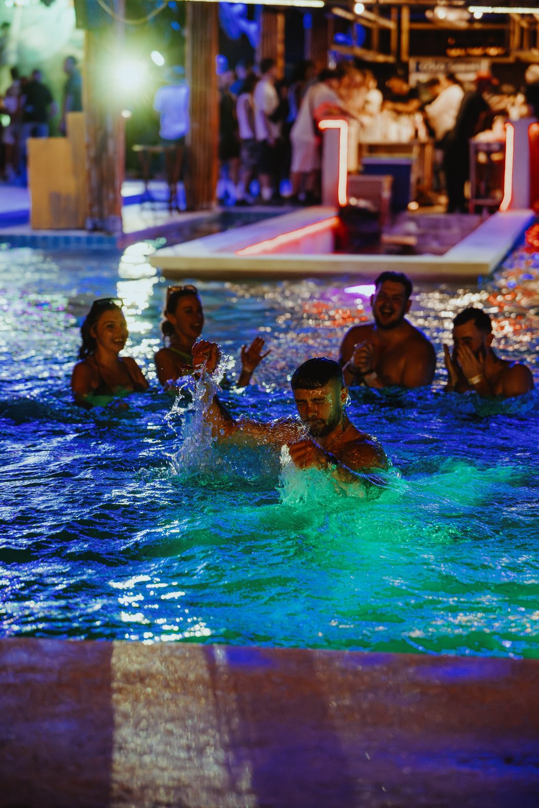 Crowd in a swimming pool at a night party lit green and blue, Phuket