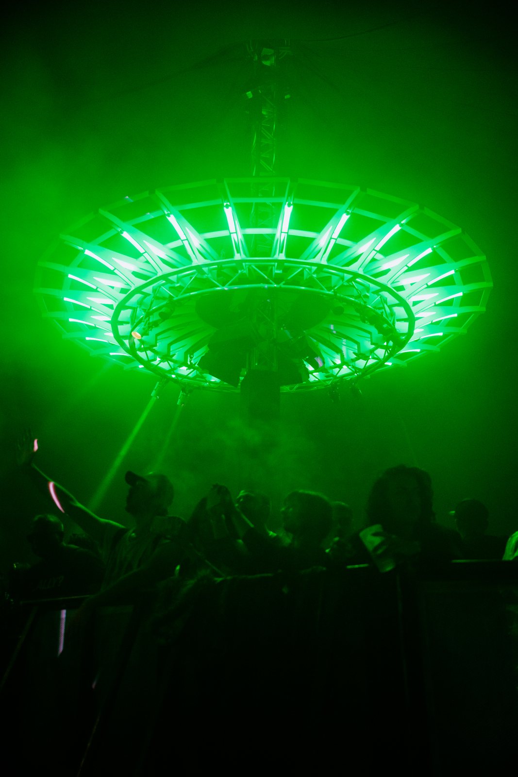 Crowd under a circular lighting rig in green smoke