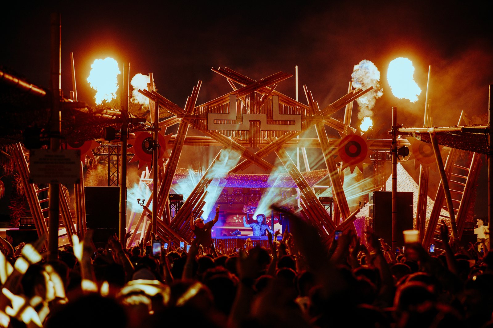 Timber festival stage at night with flame jets firing over the crowd